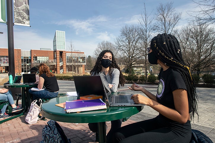 Students sit outside at a table at the Fairfax Campus