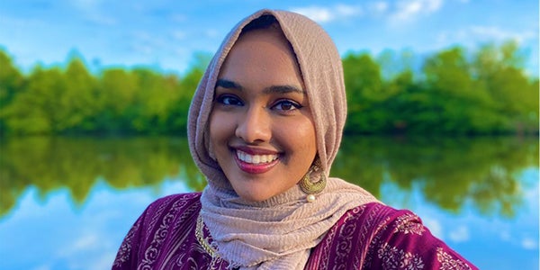 Fyzah Islam smiles at the camera as she wears a headscarf and gold earring.