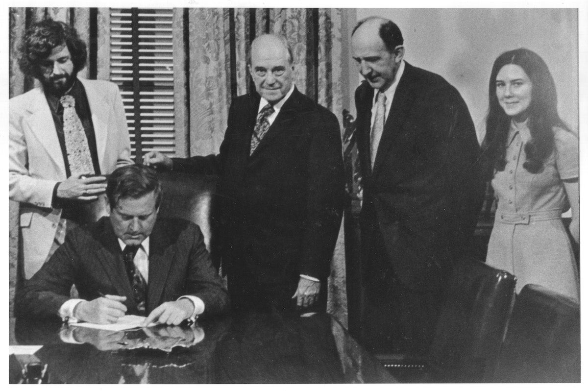 black and white photo of people standing at a desk