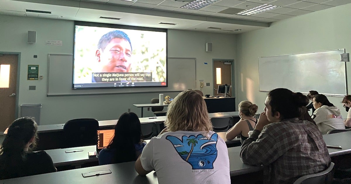 students in a room watching a film on a screen