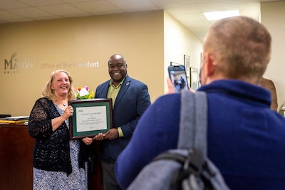 woman and a man pose for a camera with plaque