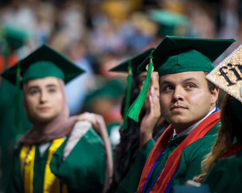 seated graduates looking attentive at the proceedings of commencement. 