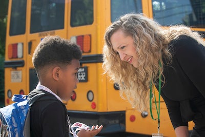 woman and boy by a school bus