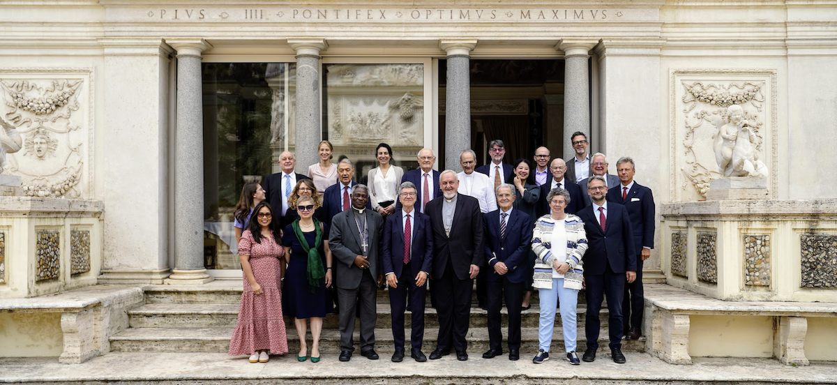 Attendees of the Pontifical Institute for Social Sciences stand for a photo together outside the Vatican. 