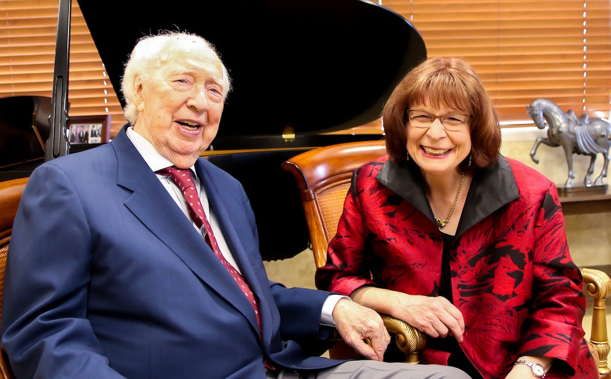 man and woman in front of a baby grand piano