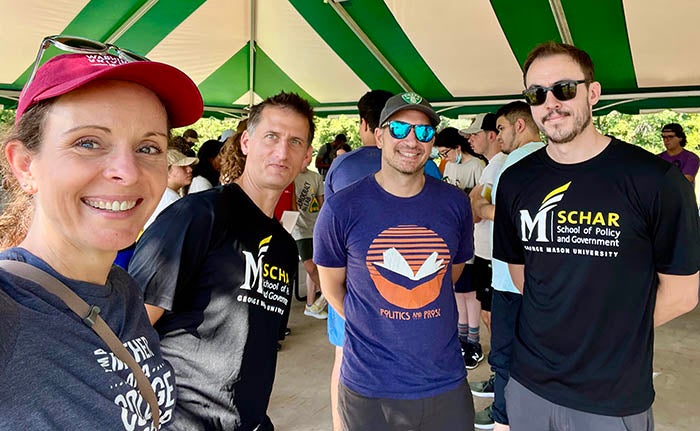 Four people in tee shirts pose for a group selfie.
