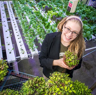 woman holding a plant in a greenhouse