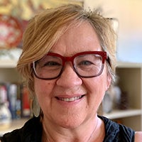 A smiling woman in eyeglasses looks at the camera.