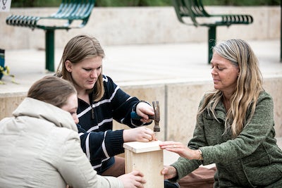 three woman work on a wooden structure