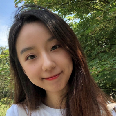 Huining Feng, IST PhD student at Mason, wears a white shirt and sits in front of a wooded background in her profile.