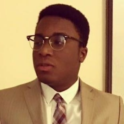 Ibifubara Iganibo, IST PhD student at Mason, wears a tan suit and glasses in his profile.