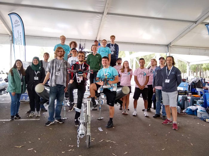 The RobotX team at Mason pose with their ship design