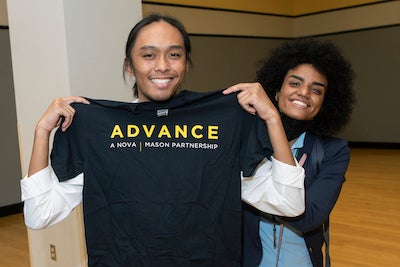 students hold up an ADVANCE shirt at event
