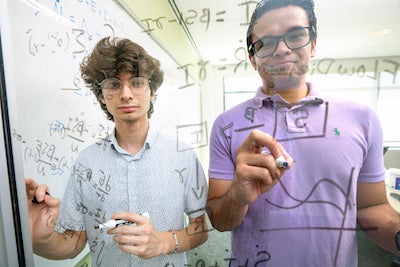 students do math on glass board