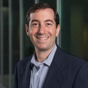 Greg Koblentz stands outside smiling while wearing a dark jacket and collared shirt.