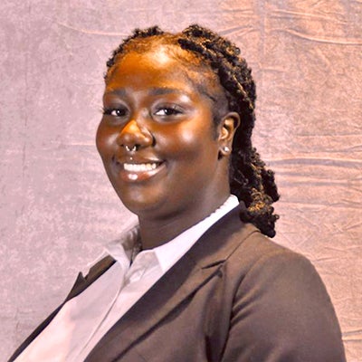 A young Black woman with her head turned smiles at the camera.