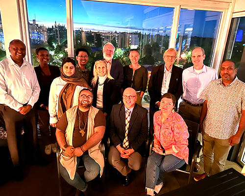 Group of people in front of a window at sunset.