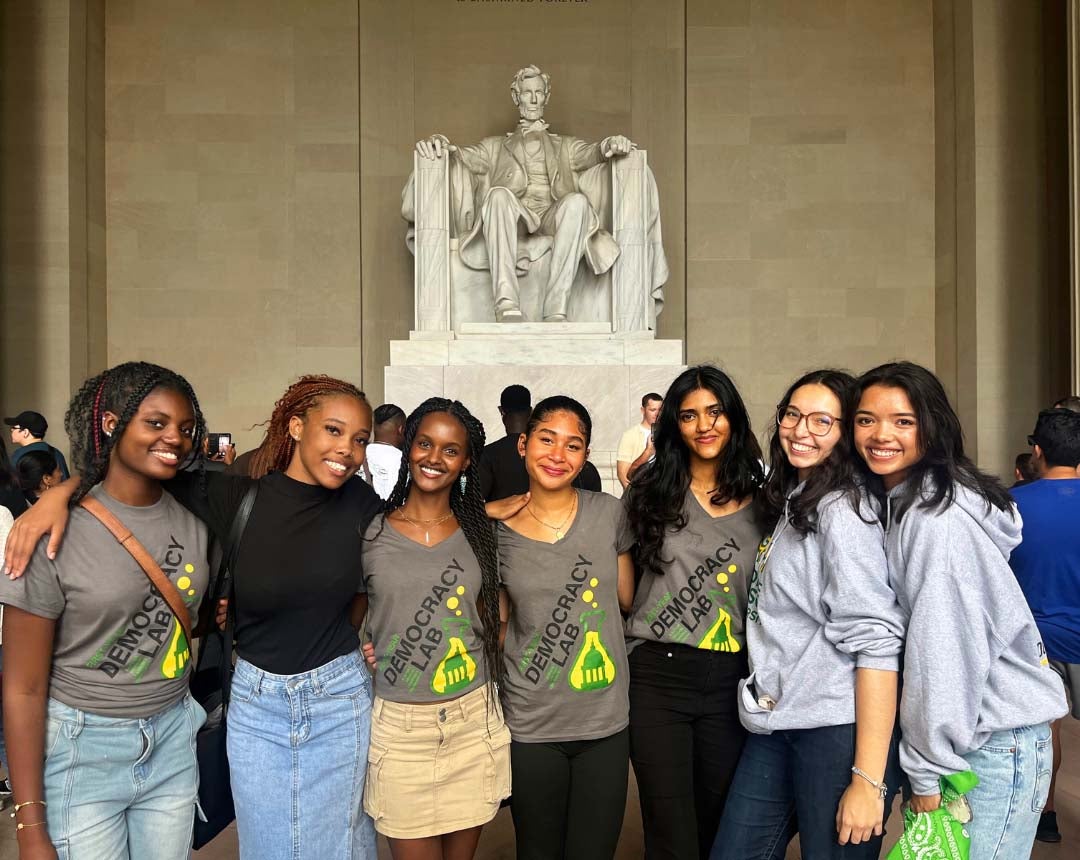 A group of seven young women pose at the Lincoln Memorial in Washington, D.C.