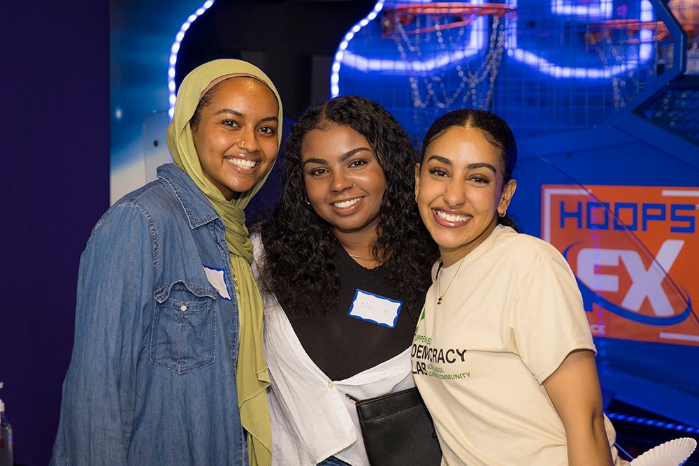 Three young women stand and smile at the camera.