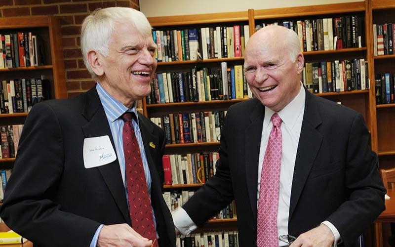 Two men in suit jackets and neckties share a laugh.