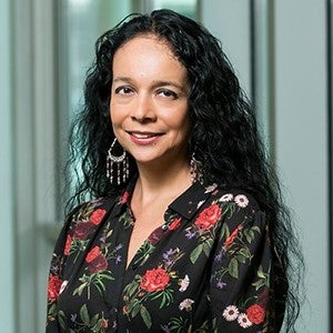 A woman with her black hair pulled back smiles at the camera.