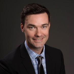 A man in a dark jacket smiles at the camera.