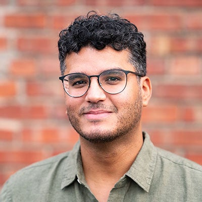 Dr. Noel Torres Rivera wearing sage green shirt and glasses