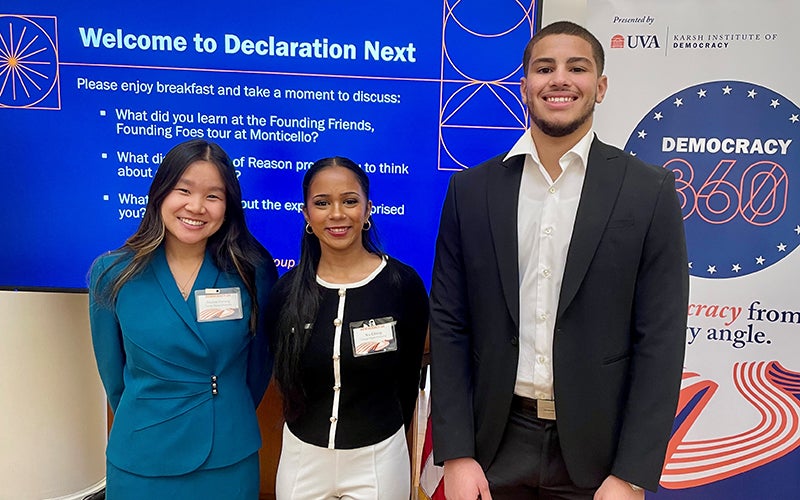 Three people stand in front of a banner.