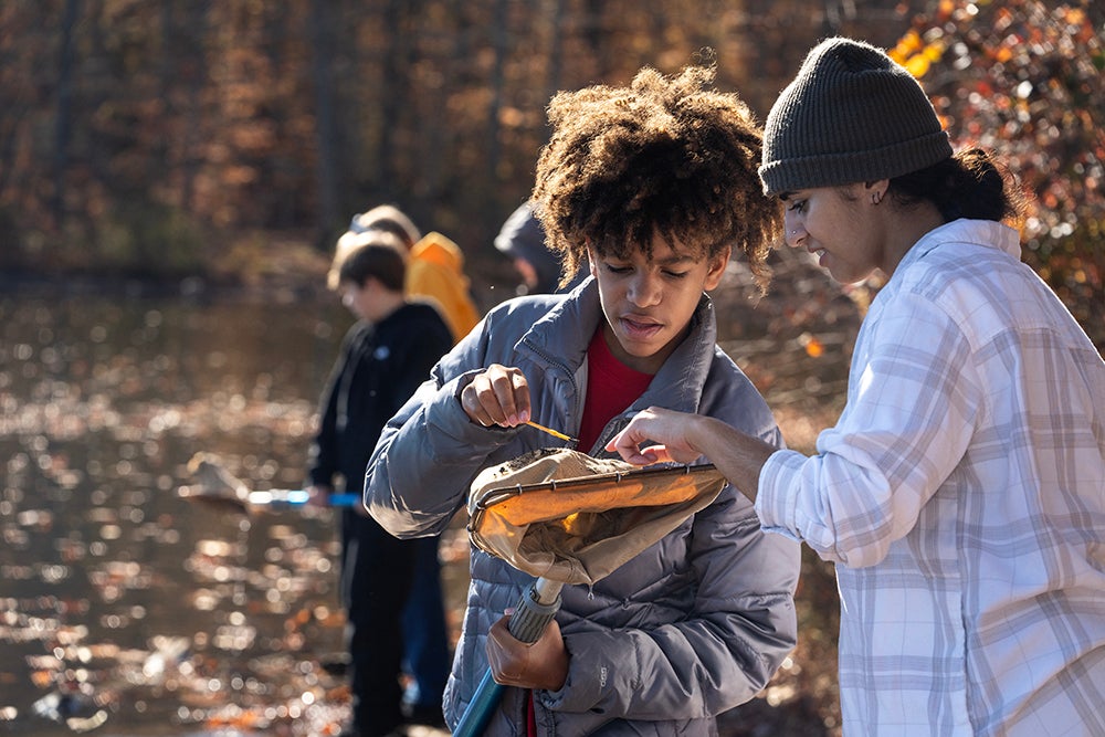 George Mason student interpreter (right) helps a student identify items in a skimmer.