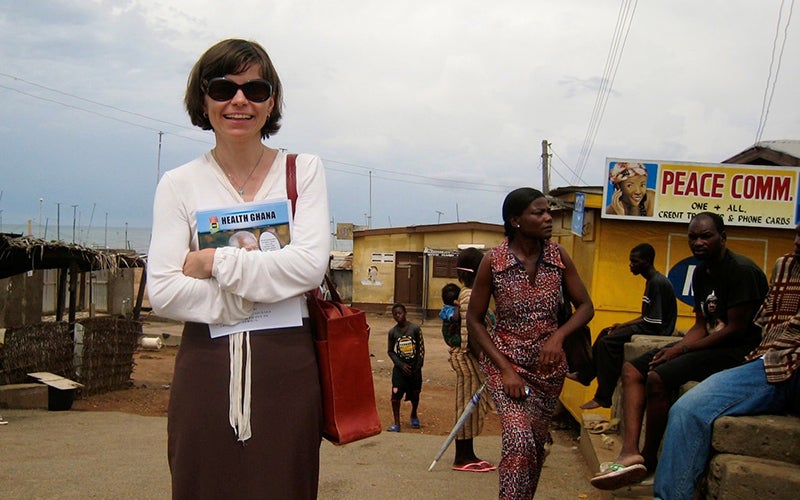 A woman in a white top holds a publication in front of her.