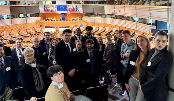 A group of people stand with their backs to a large and formal theater.