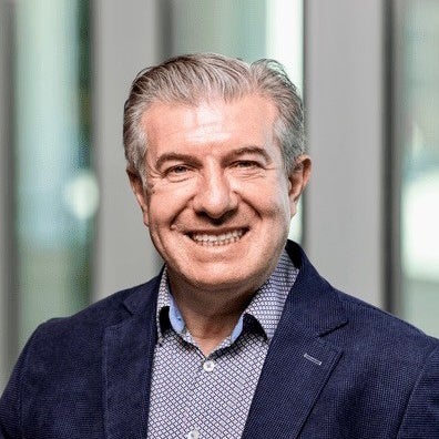 A man in a dark suit coat smiles at the camera.