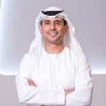 Headshot of Dr. Shareef Al Romaithi smiling and facing the camera, wearing traditional Emirati attire—a white kandura and white ghutra with black agal—against a plain background.