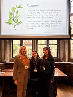 Lisa Misaki Gray, Karina Korostelina, and Christinalta Gizzi in front of a presentation slide entitled "findings"