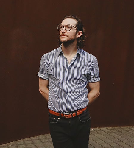 Oakley standing with arms crossed behind back looking up and to the left