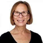 Headshot of Robbin Warner, a smiling woman with short light-brown hair and glasses, wearing a black top against a white background.