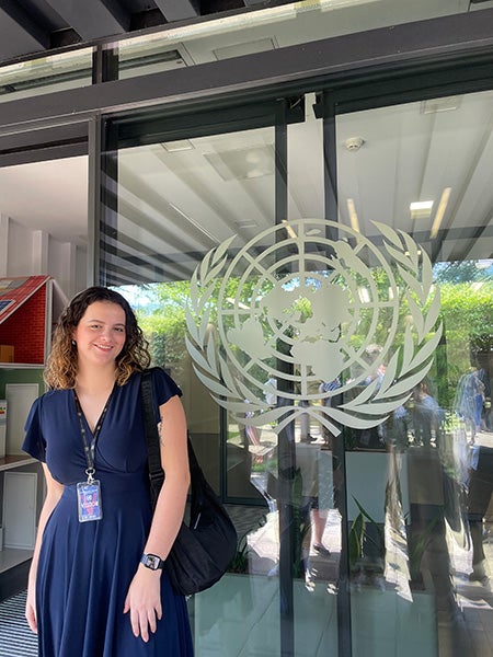 Avery Shippen standing outside of a door with the United Nations emblem