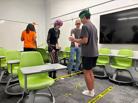 Students practice communication skills and active listening by providing instructions to a blindfolded student navigating a course