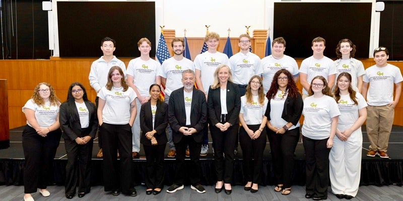 A group of students line up in two rows with faculty leader David Ramadan and Governor Abigail Spanberger.