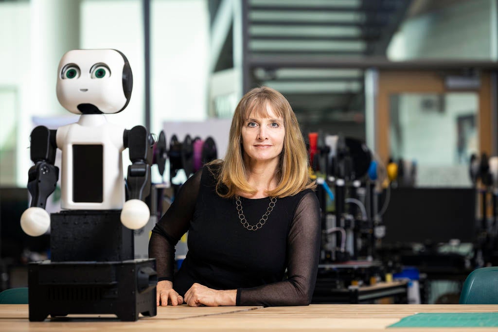 A photo of Missy Cummings, the MARC director, posing next to a robot.