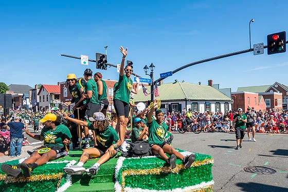 Mason basketball coach Vanessa Blair Lewis and members of the women's basketball team dressed in green Mason T-shirts on the Mason float for the Fairfax City July 4 parade