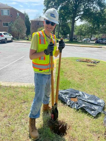 A worker digs a hole in a parking lot median