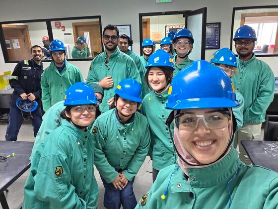 A group of college students with hard hats and protective equipment in a conference room.
