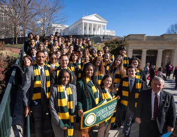 Mason students dressed with green and gold scarves pose in front of the VA state capitol.