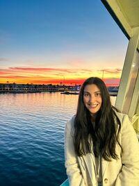 Student in front of a body of water at sunset