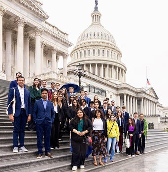 A group of people stand on the steps in front of the Capitol Building.
