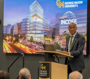 A man speaks at a podium at a conference.