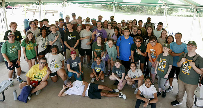 A group of students pose for the camera with one of them laying on his side.