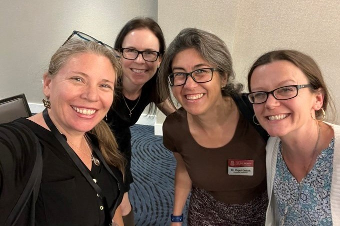 Four women smile at the camera.