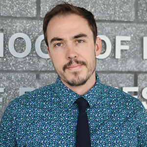 A man in a checked shirt looks at the camera.